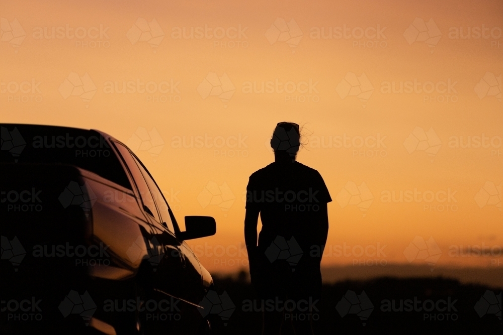 Sunset silhouette of man and car - Australian Stock Image