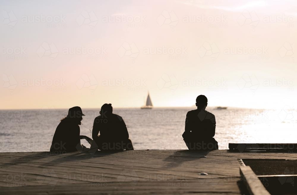 Sunset silhouette of people on a jetty : Austockphoto Sunset silhouette of people on a jetty - Australian Stock Image