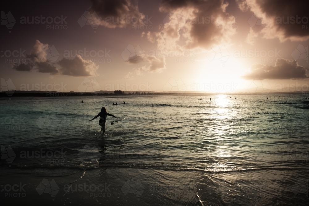 Sunset Surf at Byron Bay with female surfer - Australian Stock Image