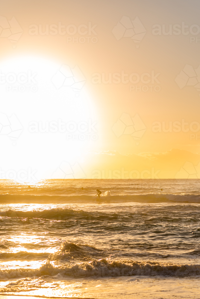 sunset surfers sesh during golden hour at the beach - Australian Stock Image