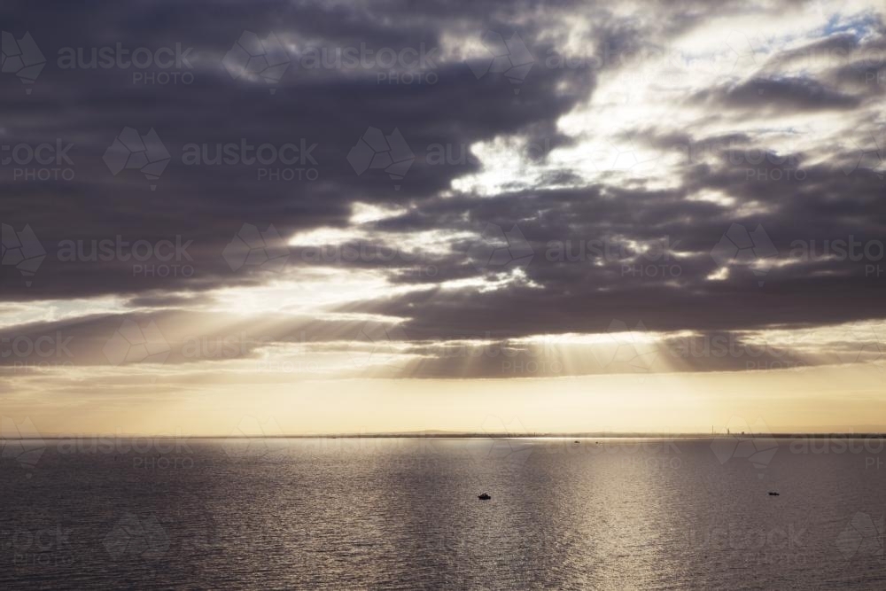 Sunset through clouds over the ocean - Australian Stock Image