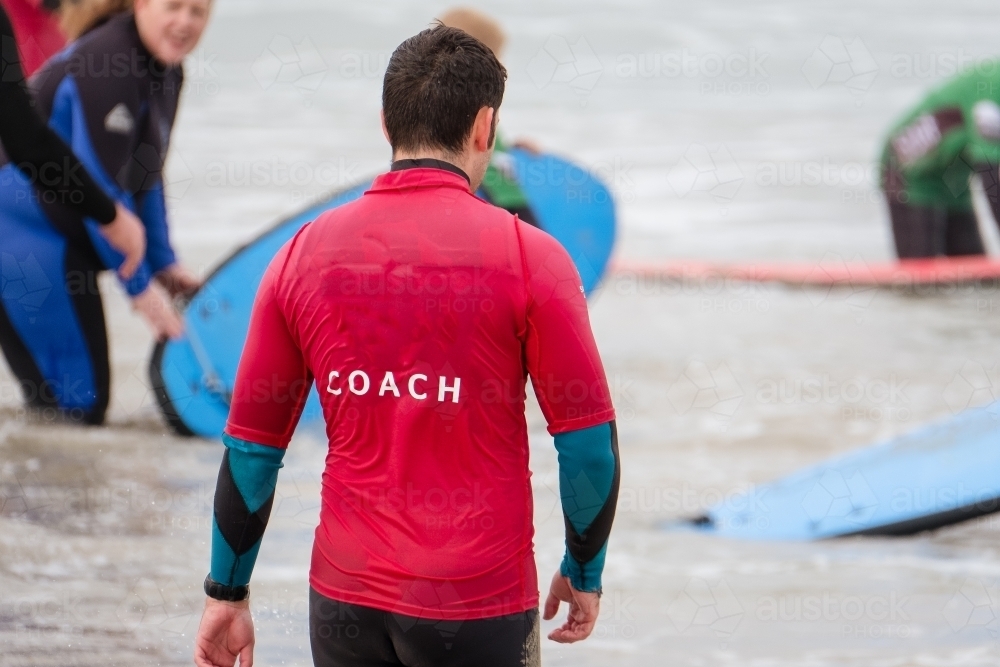 Surf coach walks into the sea. - Australian Stock Image