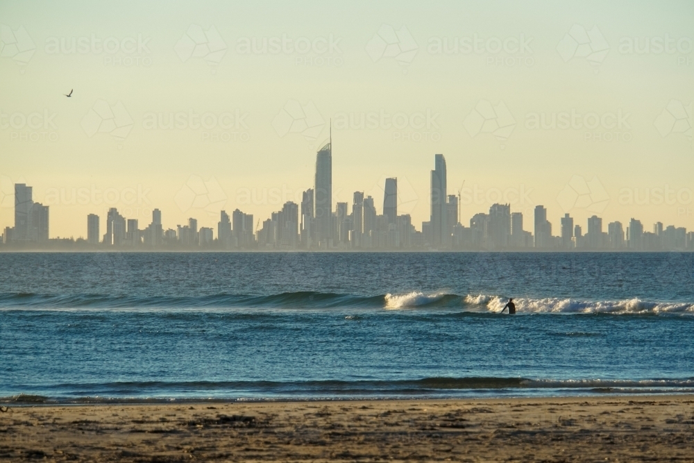 Surfer at sunset with Surfers Paradise in background - Australian Stock Image