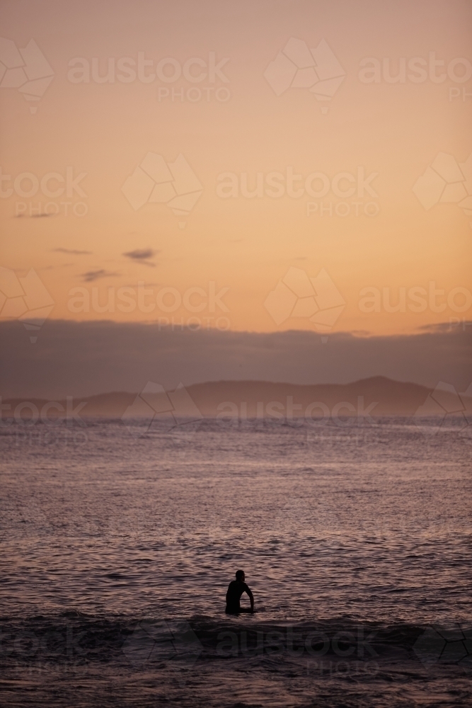 Surfer in ocean on sunrise - Australian Stock Image