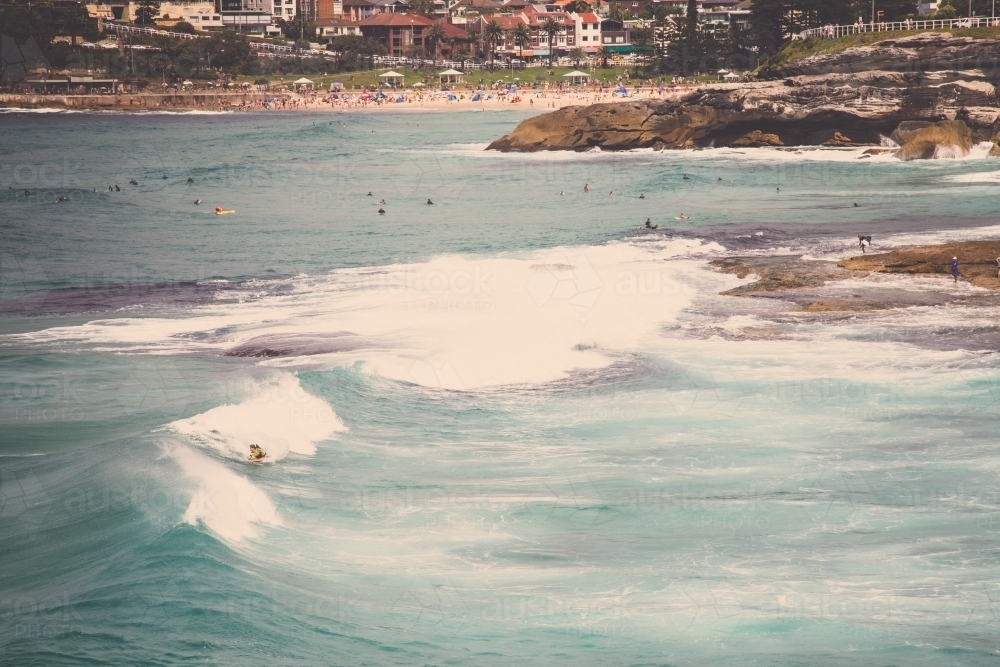 Surfer on a wave with beach in background - Australian Stock Image