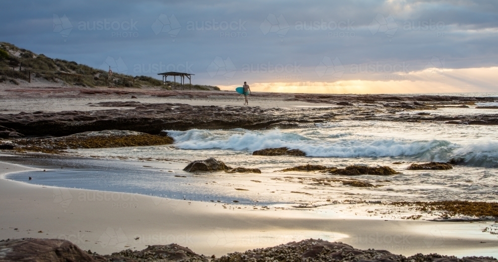 Surfer on beach at sunset - Australian Stock Image