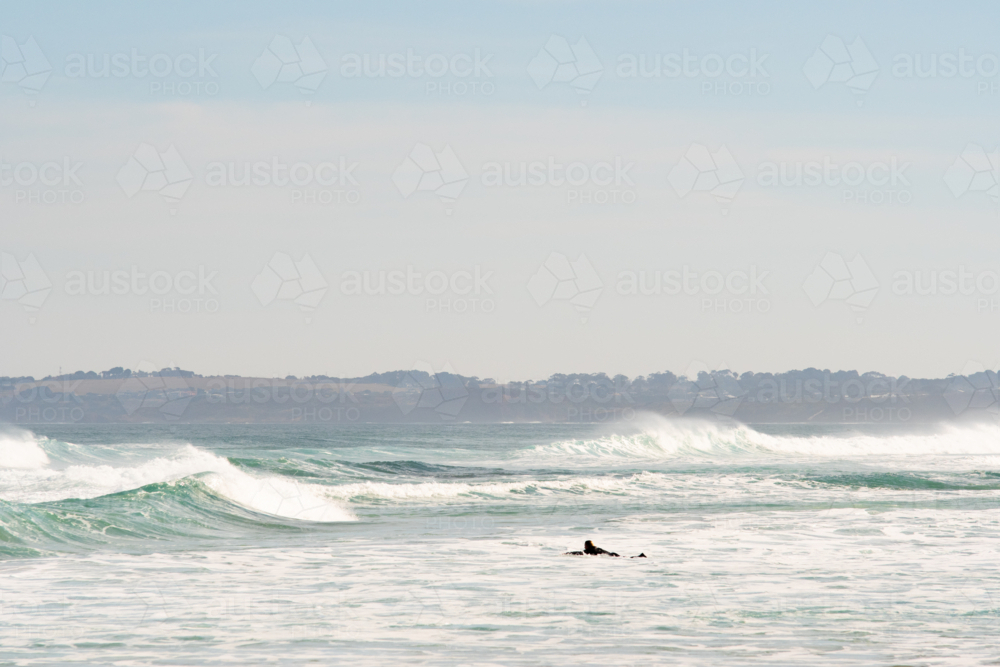 Surfer paddling out in big surf - Australian Stock Image