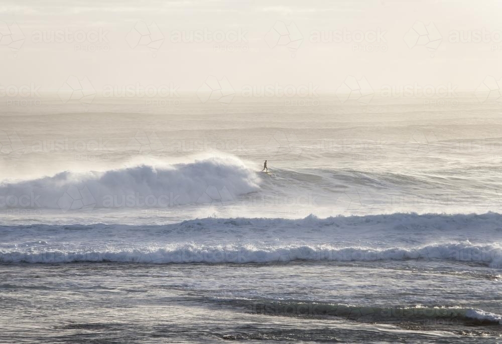 surfer riding a big wave in the distance - Australian Stock Image