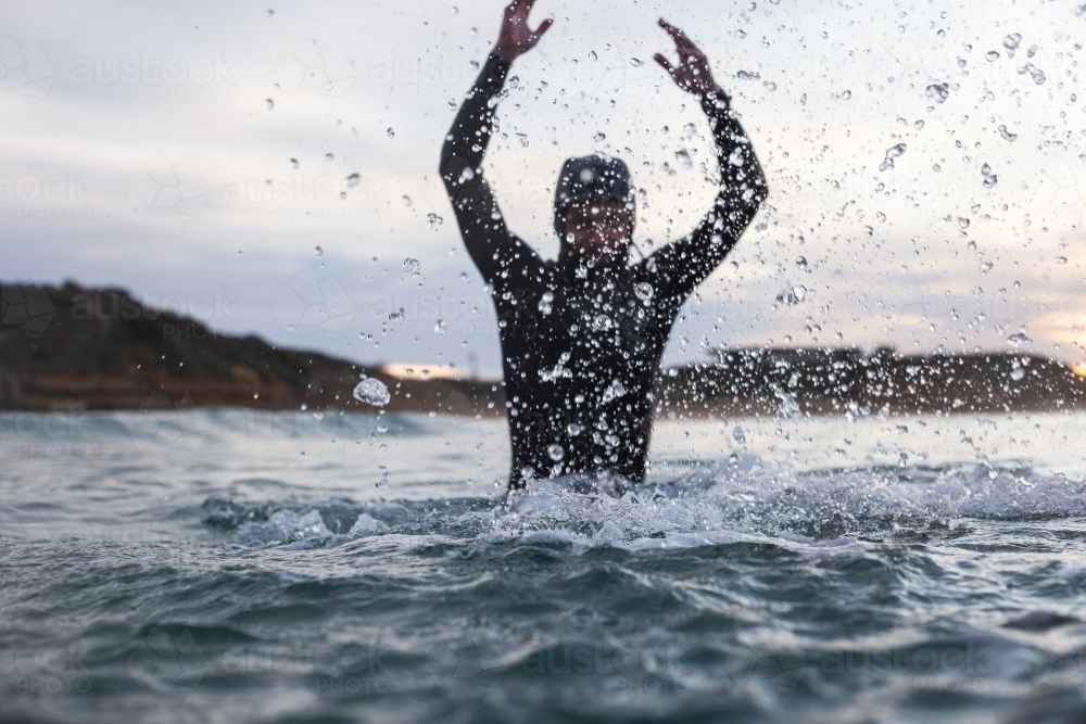 Surfer splashing in the waves at sunrise - Australian Stock Image