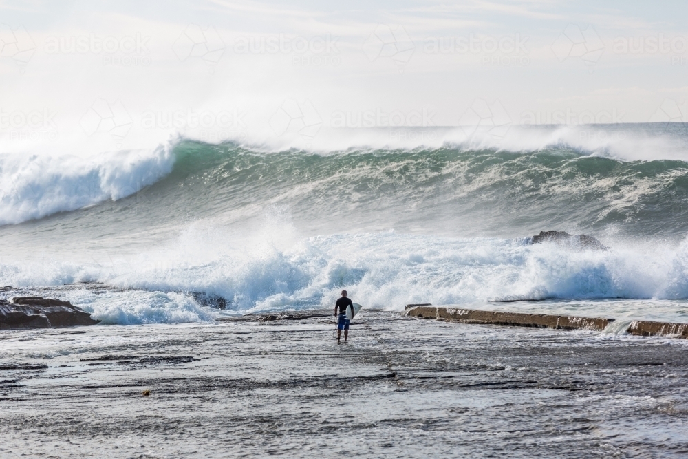 Surfer standing in the water watching the waves - Australian Stock Image