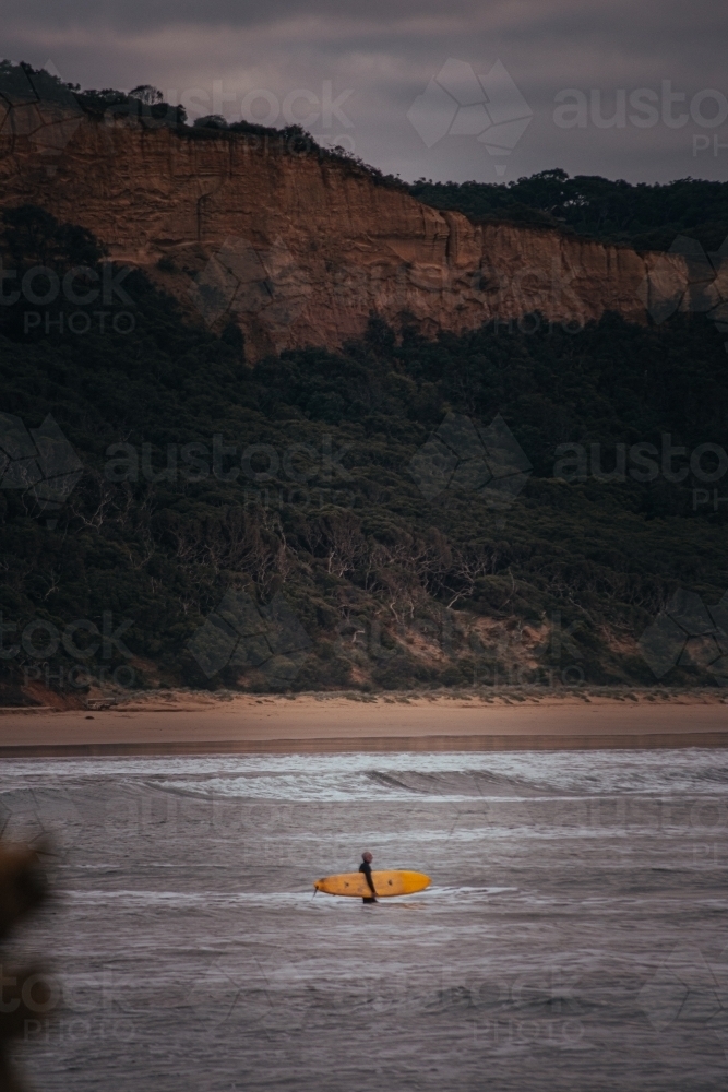 Surfer Standing on a Sand Bank in front of a Great Ocean Road Cliff - Australian Stock Image