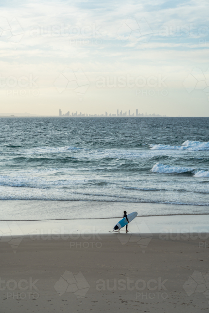 Surfer walking along the beach with surfing board - Australian Stock Image
