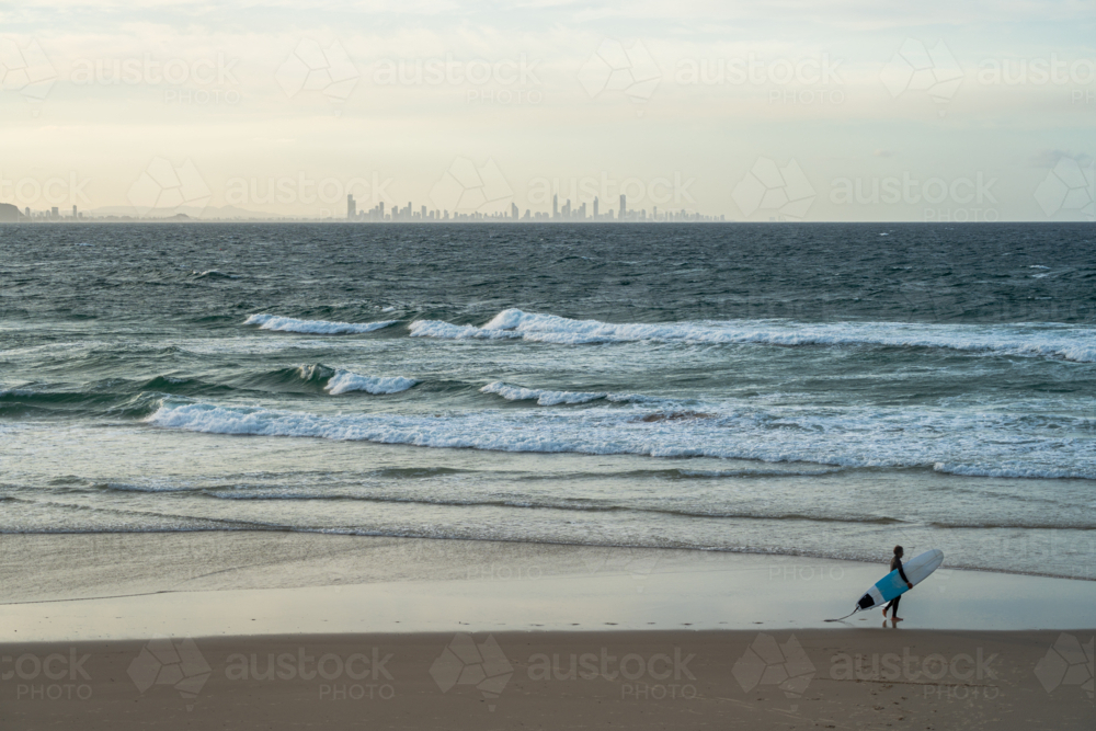 Surfer walking along the beach with surfing board - Australian Stock Image