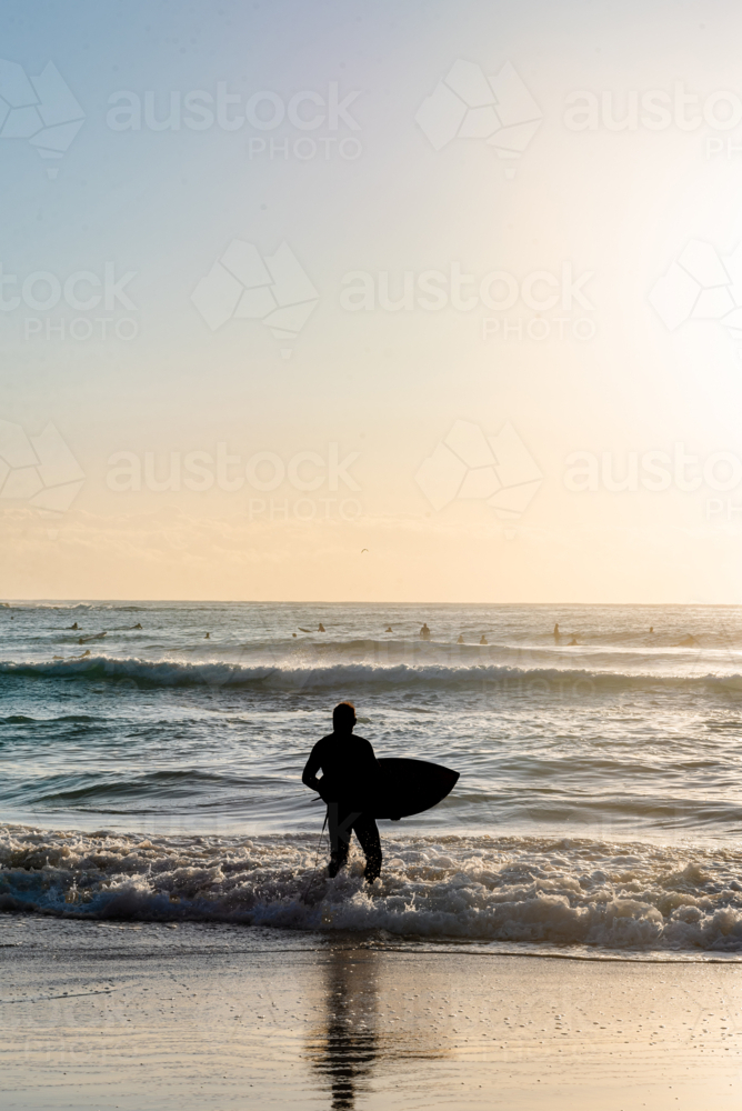 Surfer with Board Standing in Ocean at Sunrise - Australian Stock Image