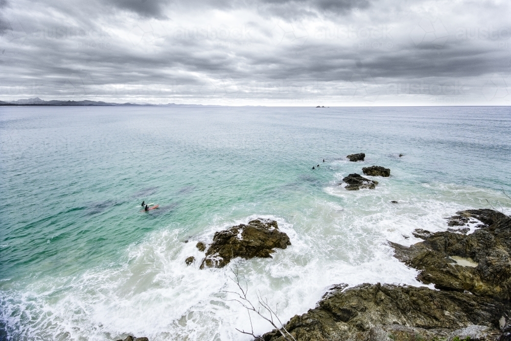 Surfers by the rocks on a stormy day - Australian Stock Image
