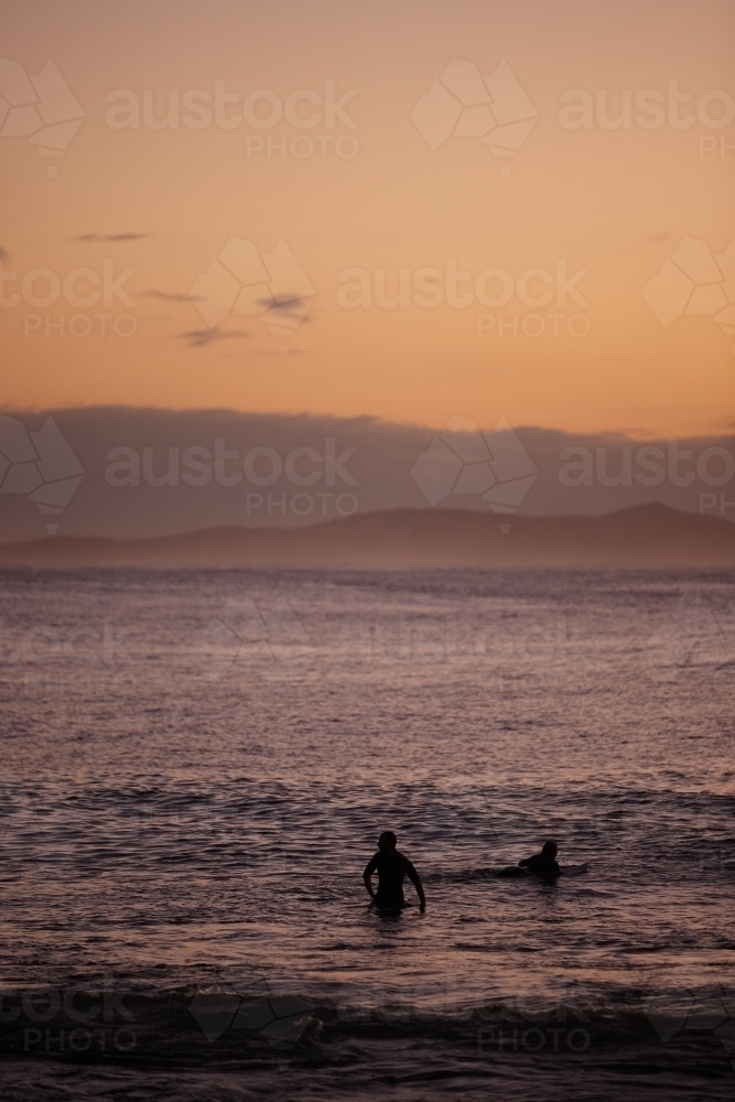 Surfers in ocean on sunrise - Australian Stock Image