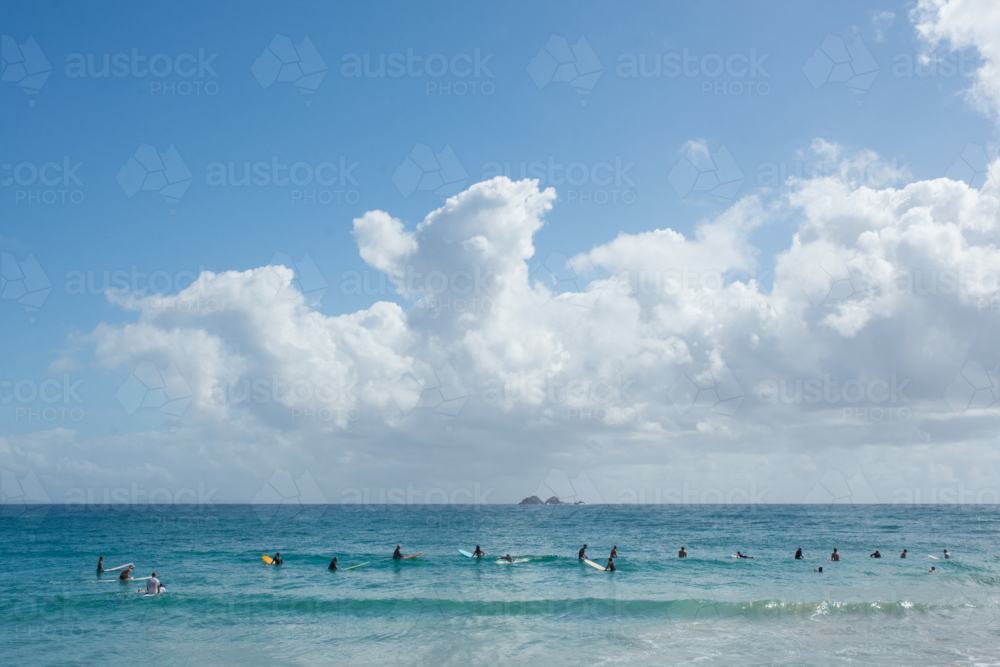 Surfers in the ocean, in a line waiting for a wave - Australian Stock Image