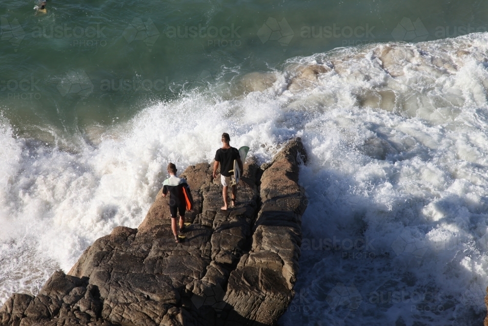 Surfers jumping off rocks - Australian Stock Image