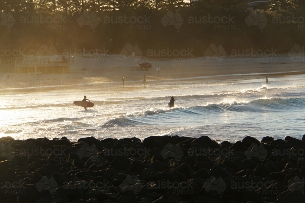 Surfers on beach at sunset - Australian Stock Image