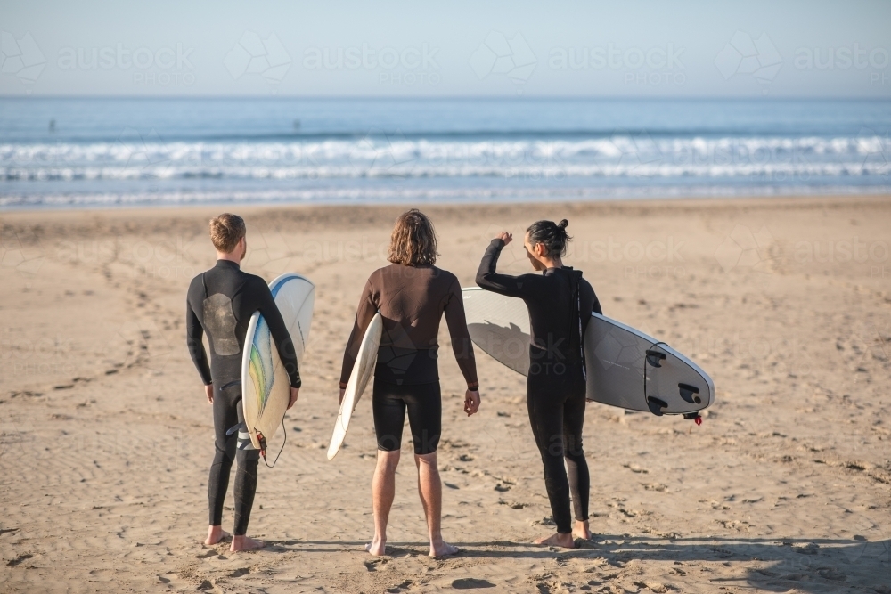 Surfers on beach looking at waves - Australian Stock Image