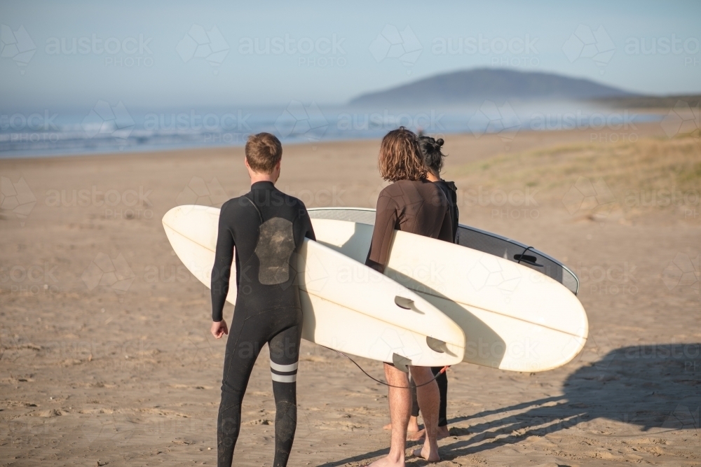 Surfers standing on beach overlooking ocean - Australian Stock Image