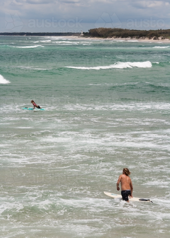 Surfers wading and padding out to a surf break - Australian Stock Image