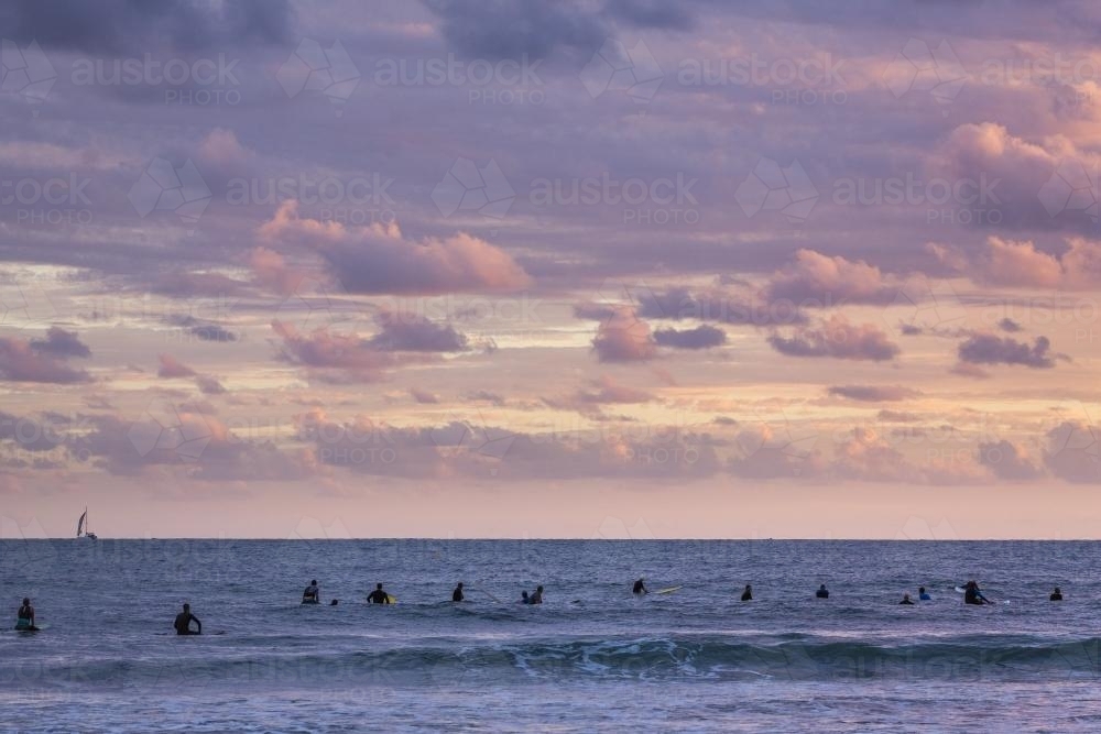 Surfers waiting for the next wave at sunrise - Australian Stock Image