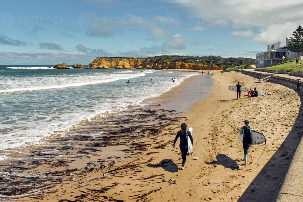 Surfers walking along a surf beach - Australian Stock Image