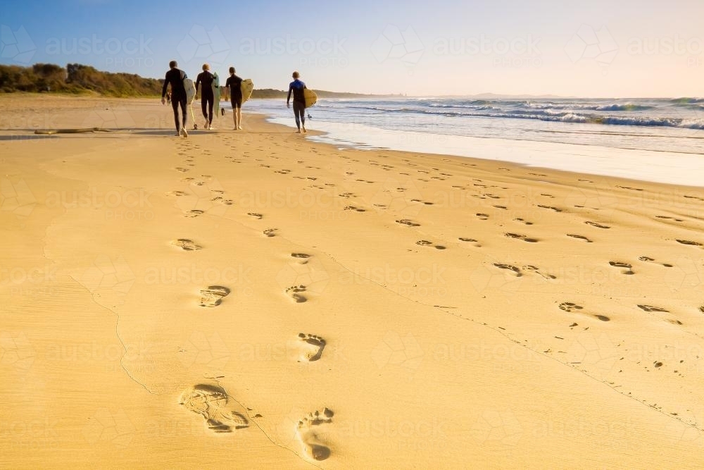 Surfers walking along the sand. - Australian Stock Image