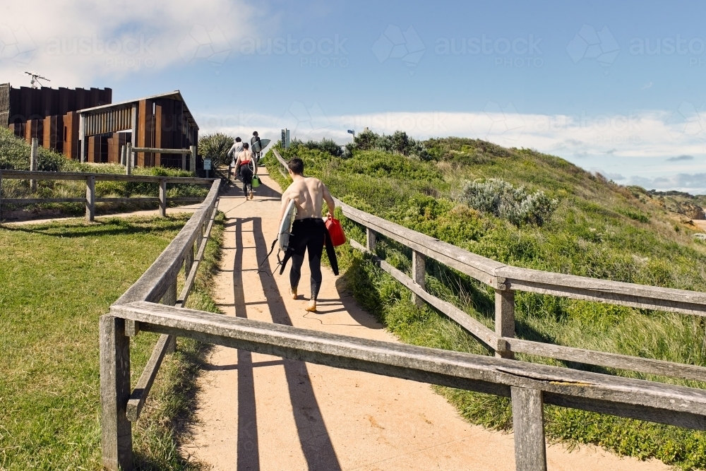 Surfers walking up a path from the beach - Australian Stock Image
