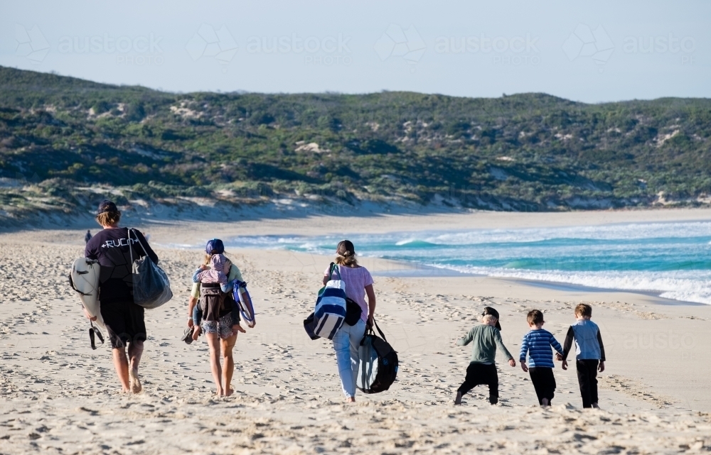 Surfing Families walking along Surf beach with boards and children - Australian Stock Image