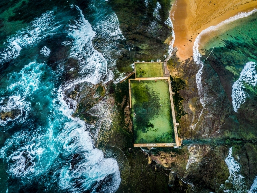 Surrounded by the oceans waves, people do their morning laps at Mona Vale ocean rock pool - Australian Stock Image