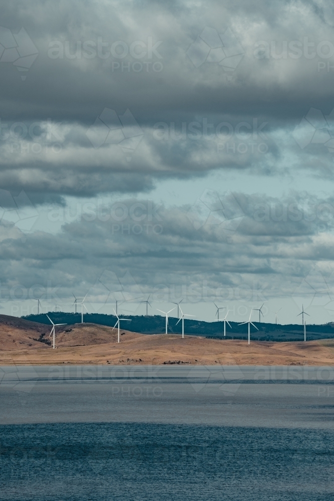 Sustainable energy wind turbines on the rolling hills behind Lake George. - Australian Stock Image