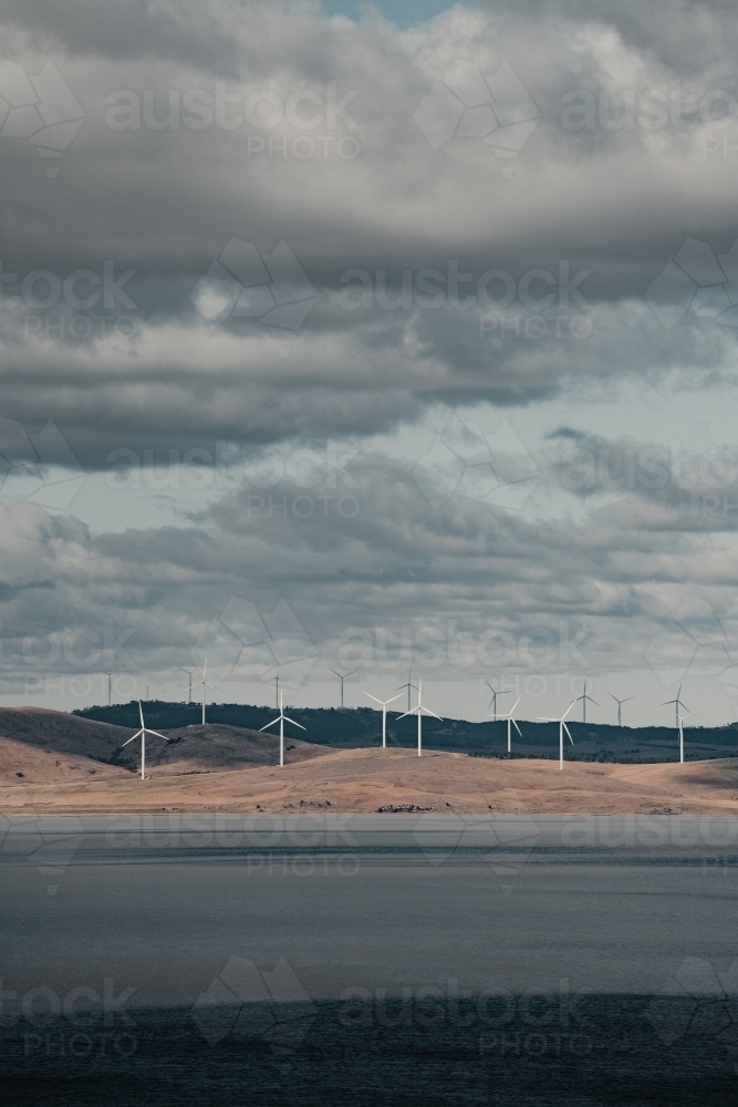 Sustainable energy wind turbines on the rolling hills behind Lake George. - Australian Stock Image