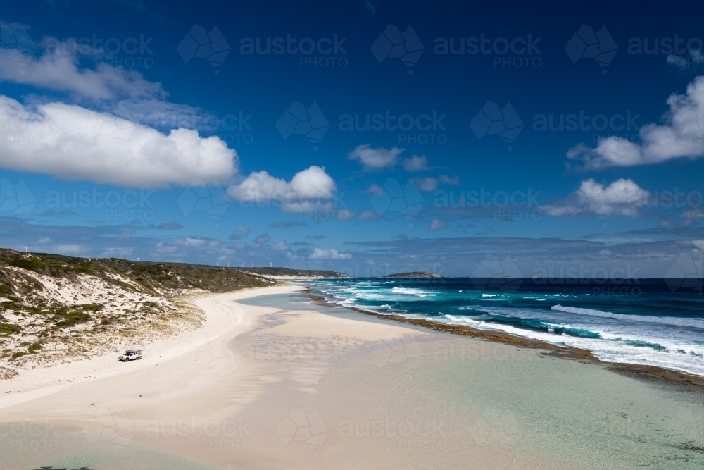 Sweeping coastal view with 4wd vehicle on beach, dark blue ocean and polarised sky - Australian Stock Image