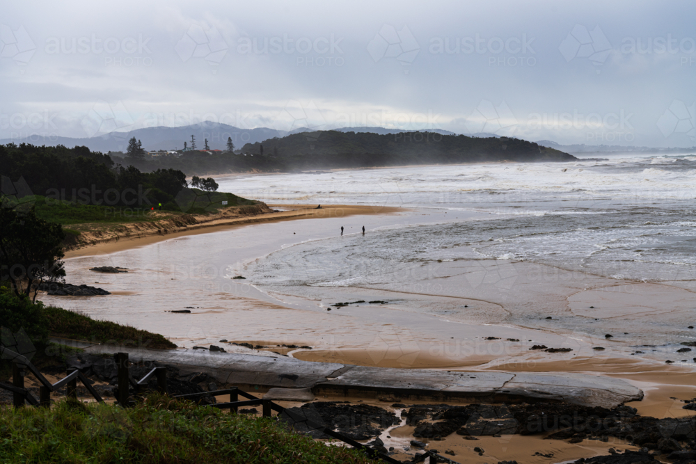 Sweeping view of coastal beaches wild weather and people walking on the shore - Australian Stock Image