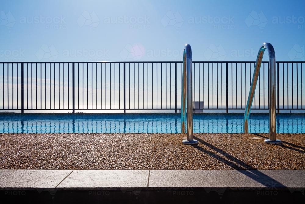 Swimming pool and fence with infinity background and pebble mix edge - Australian Stock Image
