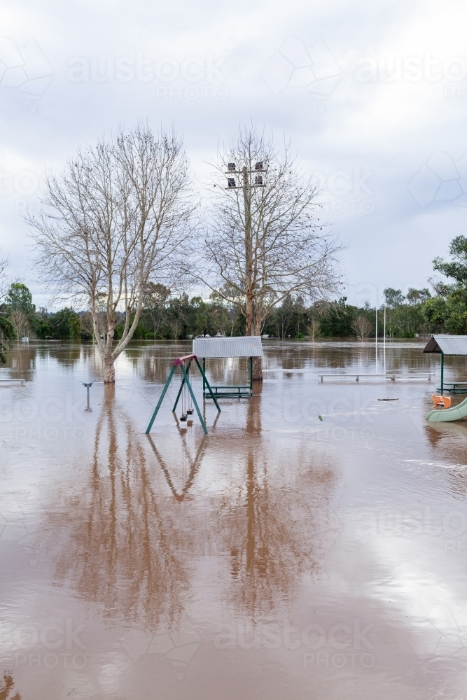Swings and slide at park under water during flood - Australian Stock Image