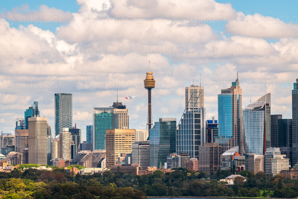 Sydney city skyline panorama with a plane taking off above while viewed across the harbour - Australian Stock Image
