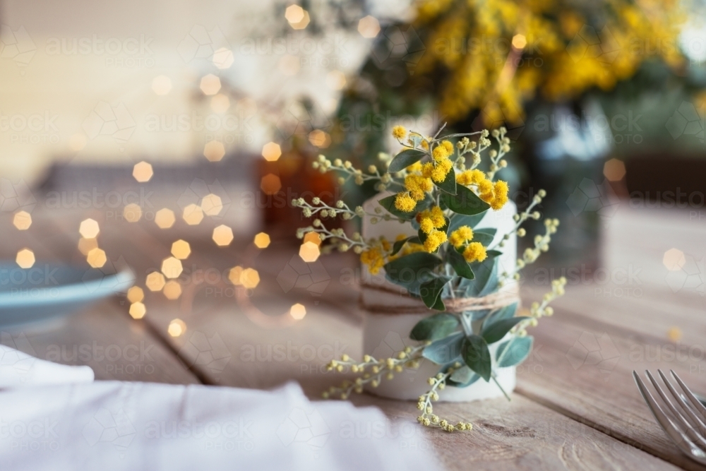 table decor with wattle sprig on a candle - Australian Stock Image