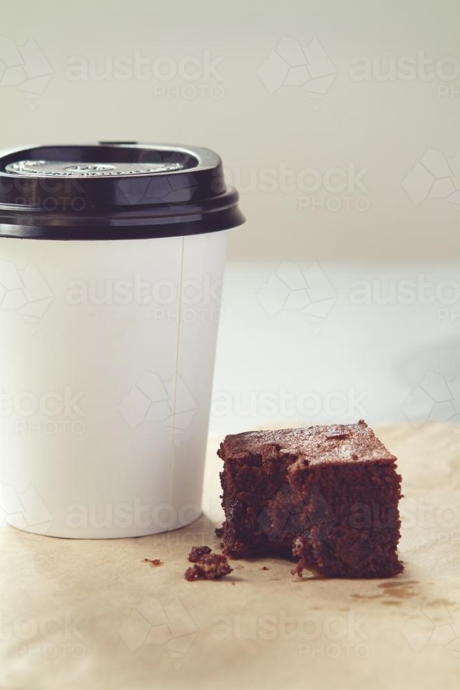 Take away coffee cup and crumbly chocolate brownie in muted tones - Australian Stock Image