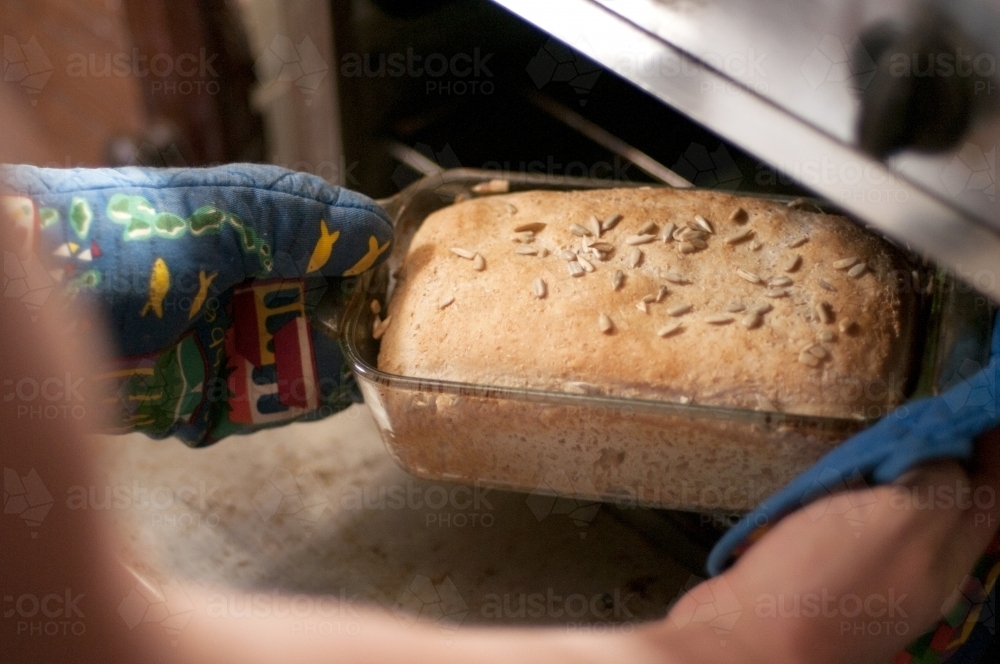 Taking home baked bread from the oven - Australian Stock Image
