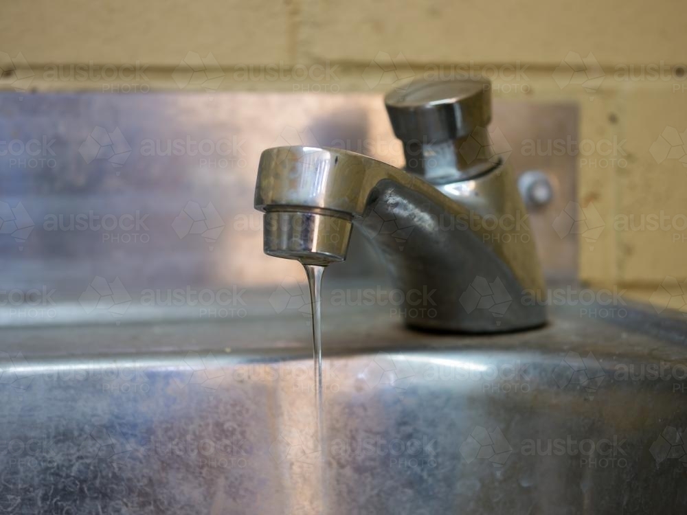 Tap leaking into a not too clean basin - Australian Stock Image