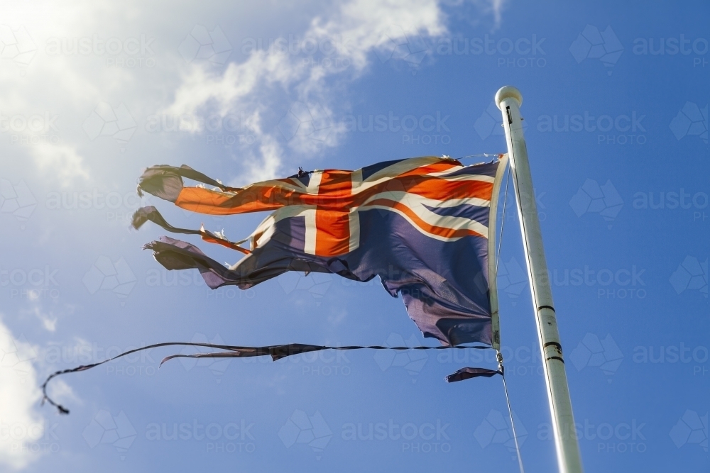 Tattered Australian flag against blue sky - Australian Stock Image