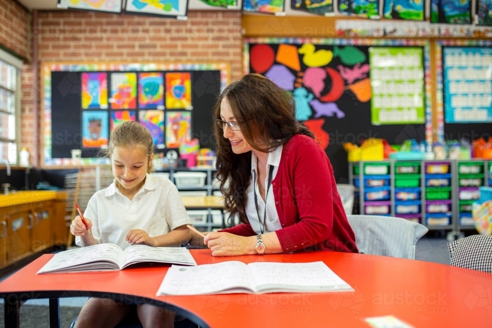 Image of Teacher Helping Young Student in Classroom - Austockphoto