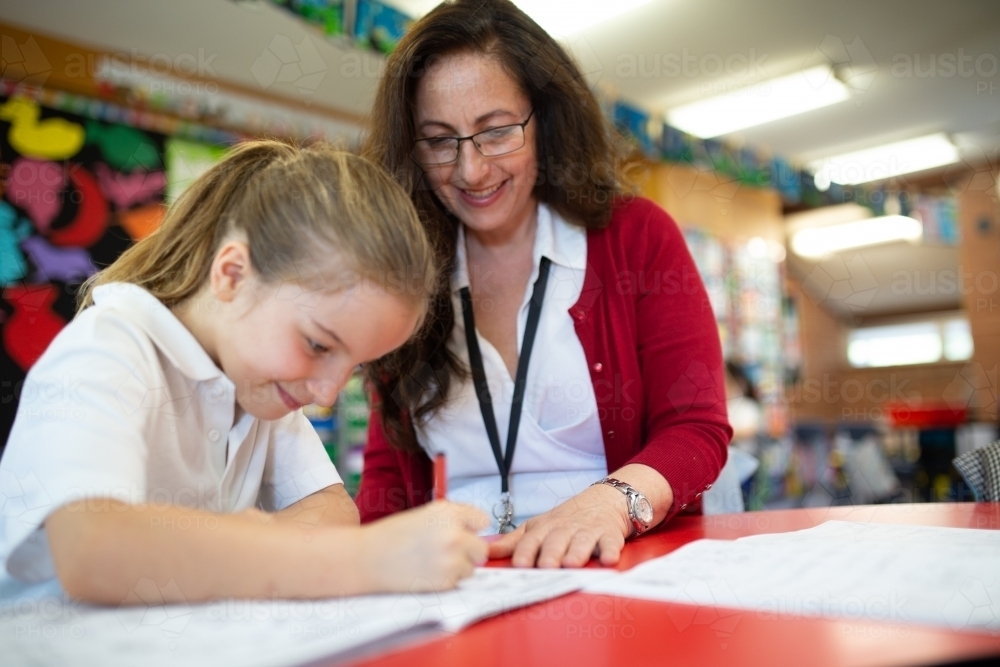 Teacher Smiling at Student Writing - Australian Stock Image