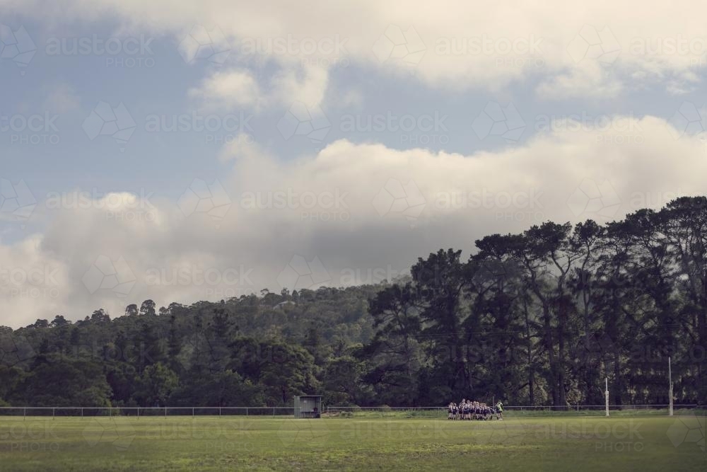 Team huddle on scenic football field - Australian Stock Image