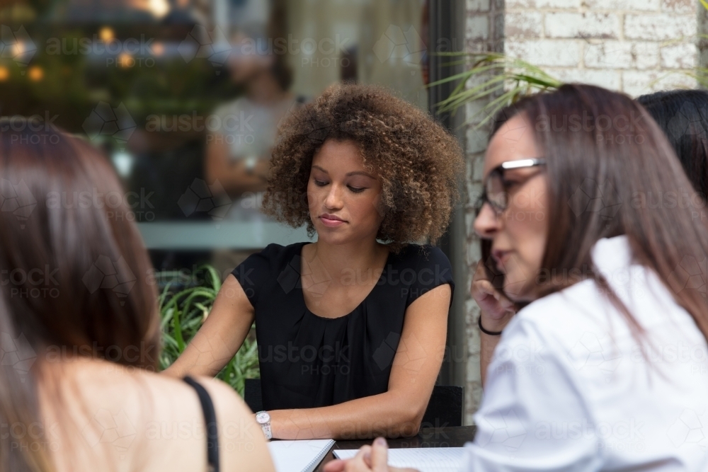 Team of women collaborating outside at a table together - Australian Stock Image