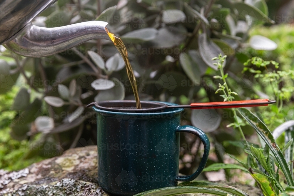 Teapot pouring tea into mug with filter - Australian Stock Image