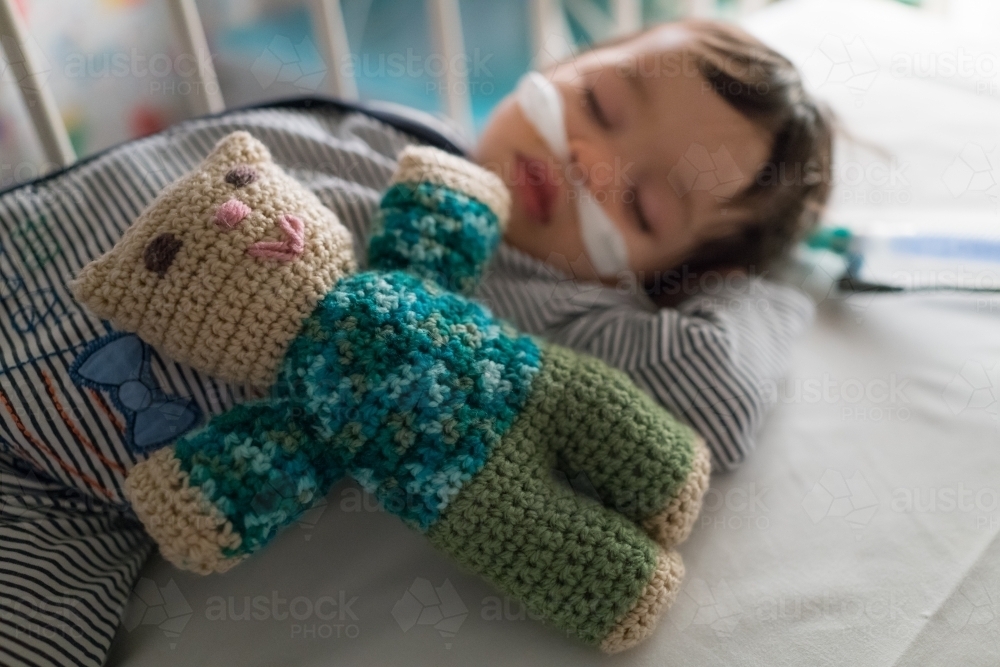 Teddy lying on a sleeping one year old being treated with oxygen therapy - Australian Stock Image